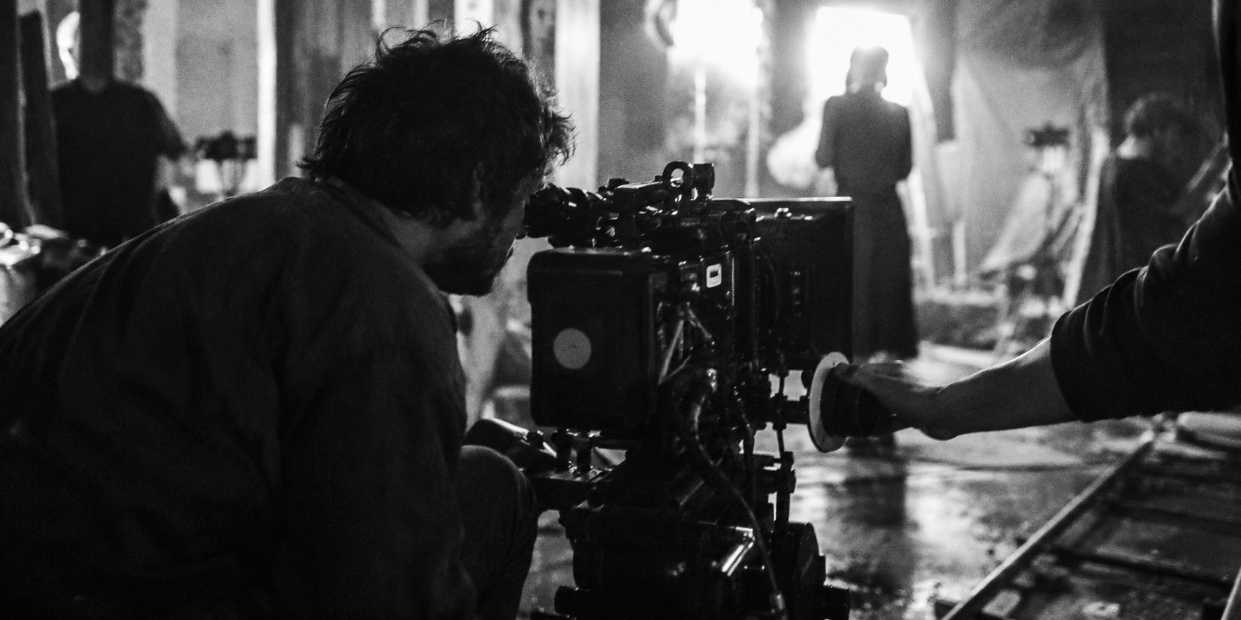 A camera operator crouched behind a cinema camera on set